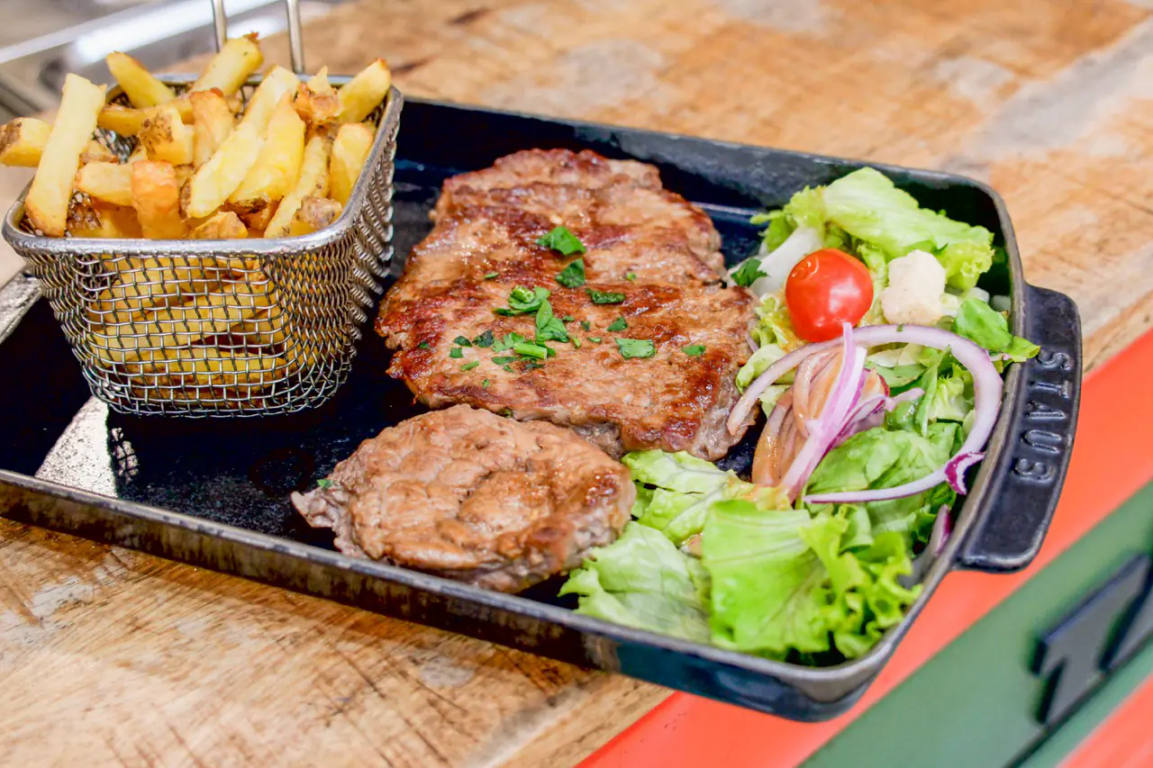 Grillades, frites maison et salade servies sur une planche