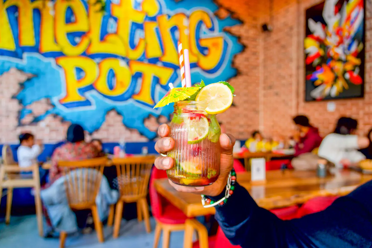 Cocktail aux agrumes levé devant la fresque graffiti Melting Pot